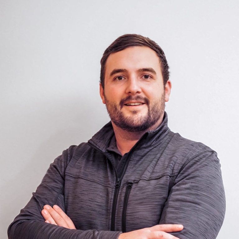 David Fuchs Inhaber Fuxx Elektrotechnik Mann mit kurzem Bart und dunklem Pullover, lächelt und steht mit verschränkten Armen. David Fuchs Inhaber Fuxx Elektrotechnik
